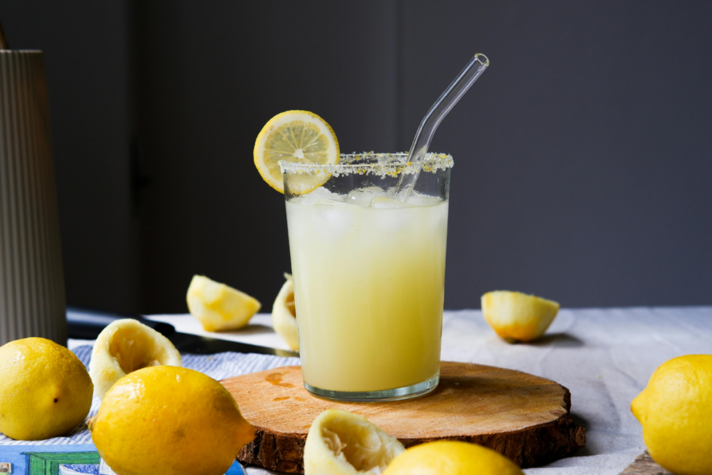 Glass of fresh lemon juice with lemon slices on a wooden table, representing metabolic health and hydration.