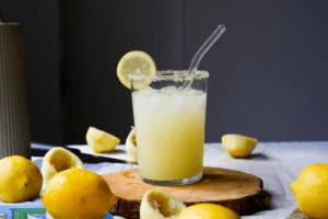 Glass of fresh lemon juice with lemon slices on a wooden table, representing metabolic health and hydration.